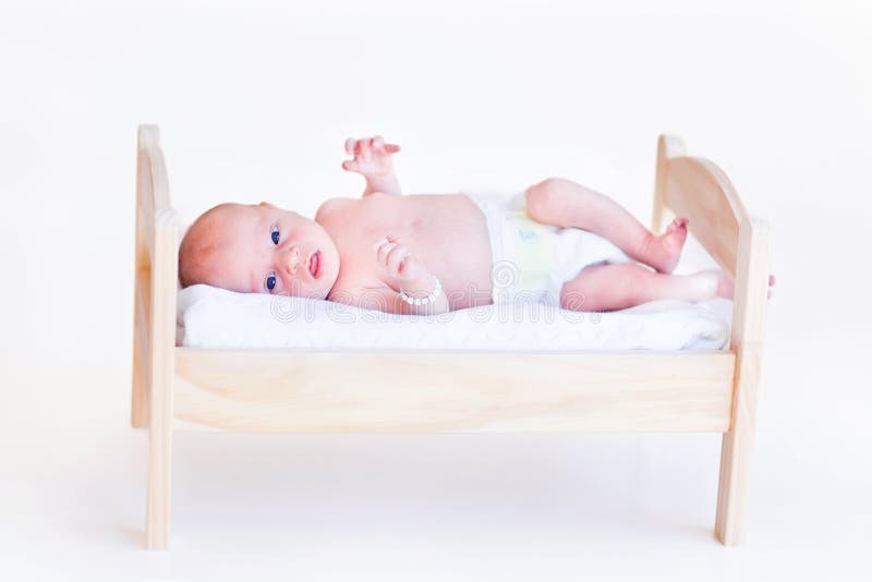 Bébé nouveau-né mignon dans une couche-culotte s'étendant dans un lit de jouet photo libre de droits Bébé nouveau-né mignon dans une couche-culotte s'étendant dans un lit de jouet photo libre de droits