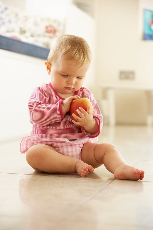 Bébé s'asseyant sur l'étage regardant Apple