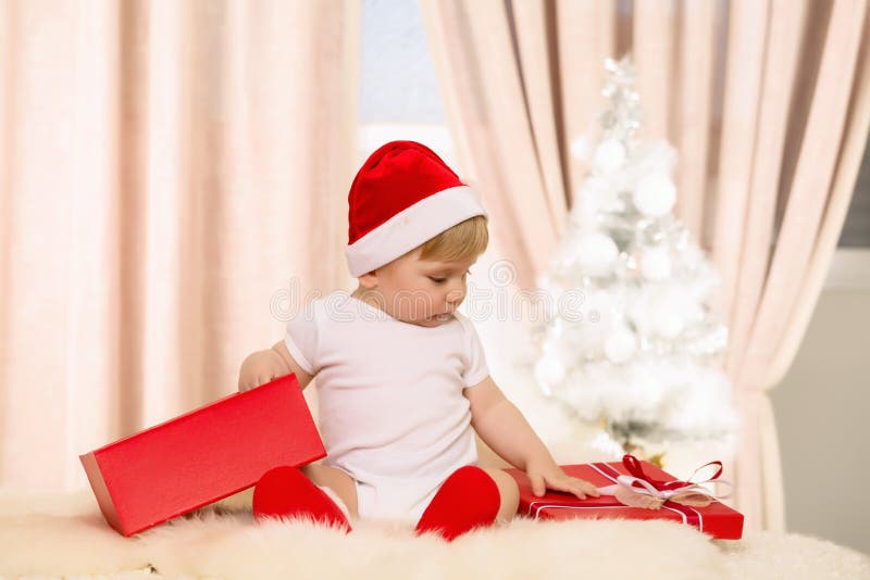Bébé Santa ouvrant un grand boîte-cadeau rouge photos libres de droits Bébé Santa ouvrant un grand boîte-cadeau rouge photos libres de droits