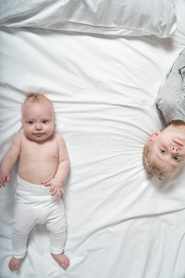 BÃ©bÃ© Ã©tonnÃ© et frÃ¨re aÃ®nÃ© sont couchÃ©s sur le lit. Vue supÃ©rieure photo libre de droits