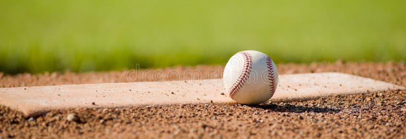 A white leather baseball lying on top of the pitcher's mound at a baseball field with copy space. A white leather baseball lying on top of the pitcher's mound at a baseball field with copy space