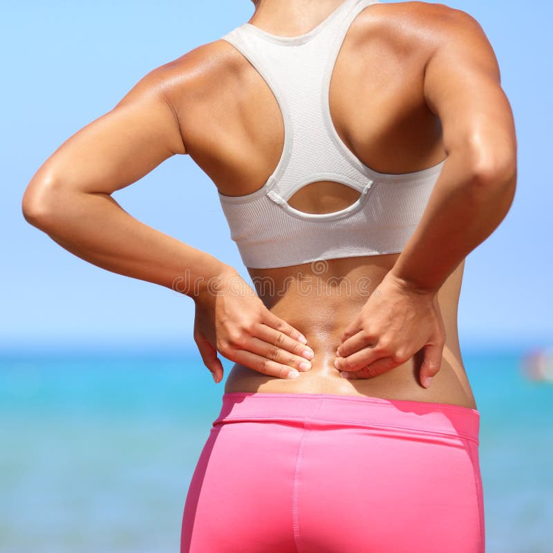 Back pain - woman having painful muscle injury in lower back. Fitness girl sport girl with sports injury outdoor on beach. Back pain - woman having painful muscle injury in lower back. Fitness girl sport girl with sports injury outdoor on beach.