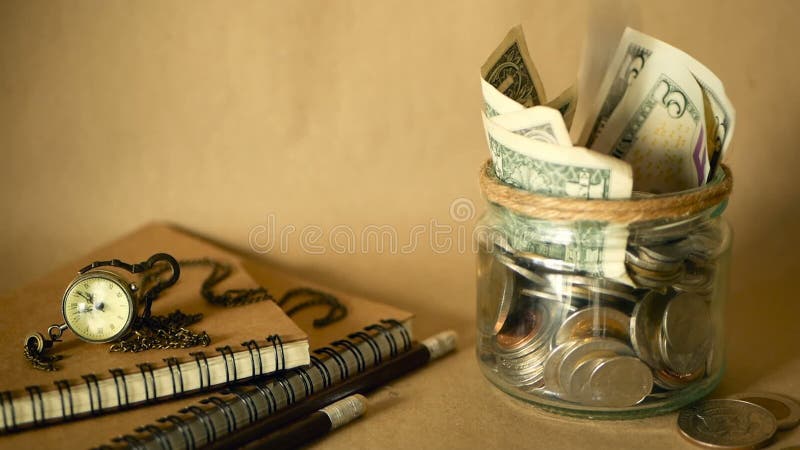 Böcker med den glass encentmyntet skorrar fyllt med mynt och sedlar Skolavgift- eller utbildningsfinansieringbegrepp Stipendiumpe