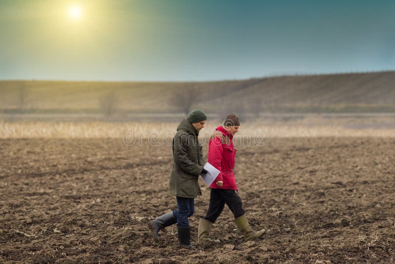Two farmers walking on plowed field in winter time. Two farmers walking on plowed field in winter time