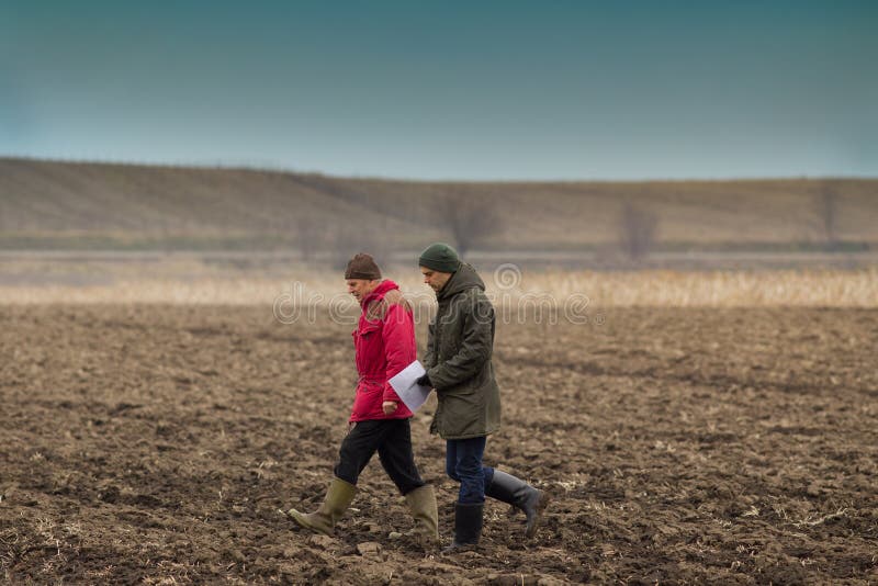 Two farmers walking on plowed field in winter time. Two farmers walking on plowed field in winter time