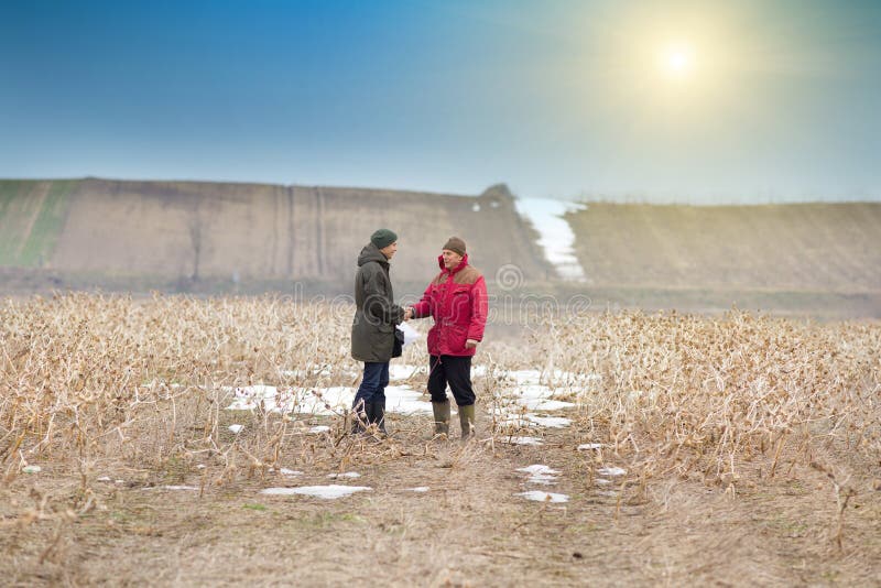 Two men shaking hands on farmland in winter time. Two men shaking hands on farmland in winter time