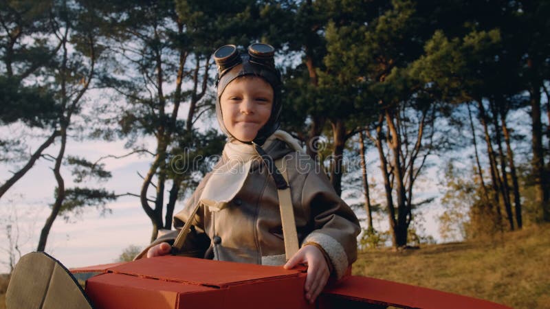 Băiat aviator fericit stând sub copaci în avion carton costum cu ochelari de epocă jucând pilot încet. stock footage