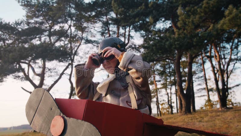 Băiat pilot fericit și serios sub arbori în avion de cardcarton distractiv costum poartă ochelari de aviație de vintage. stock video footage