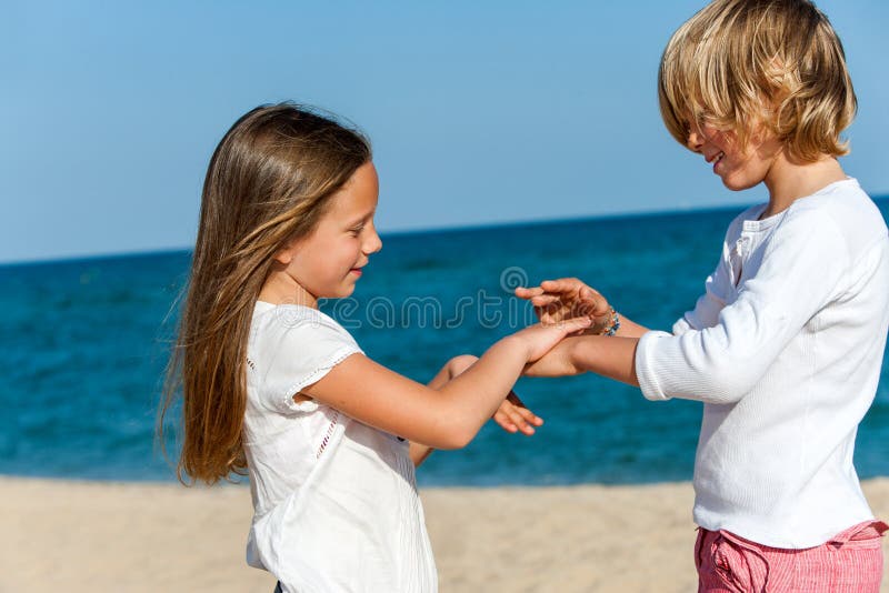 Băiat și fată jucând joc de mână pe plajă. stock photo