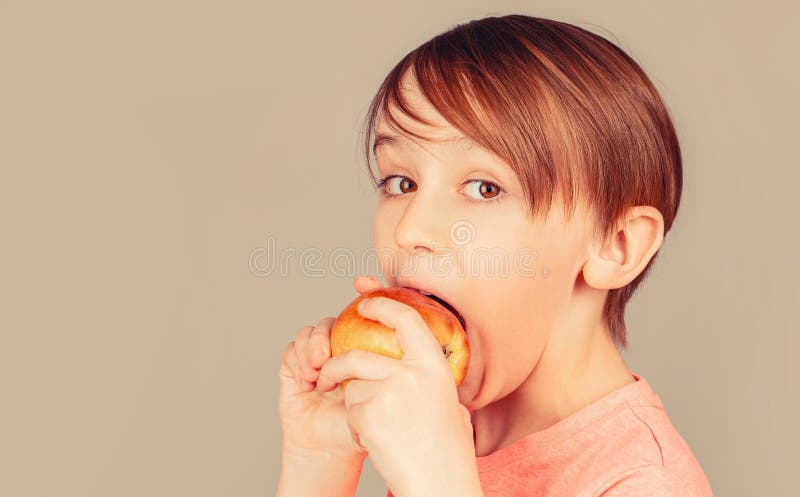 Băiețelul mâncând mere și zâmbind. băiatul zâmbește și are dinți albi sănătoși. băiețel mâncând mere. mere de băiat stock photography