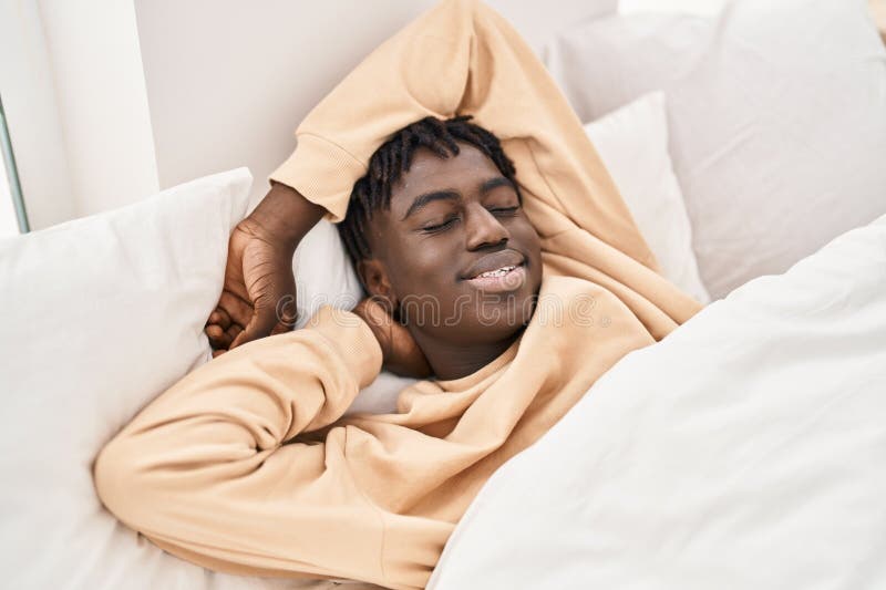 Bărbat american african care stă în pat dormind în dormitor stock photo