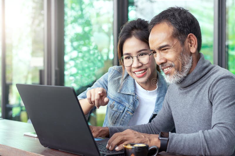 Bărbat asiatic atrăgător, cu barbă scurtă și elegantă, care se uită la un laptop cu ochelari de adolescent, o femeie cu hipster în royalty free stock images