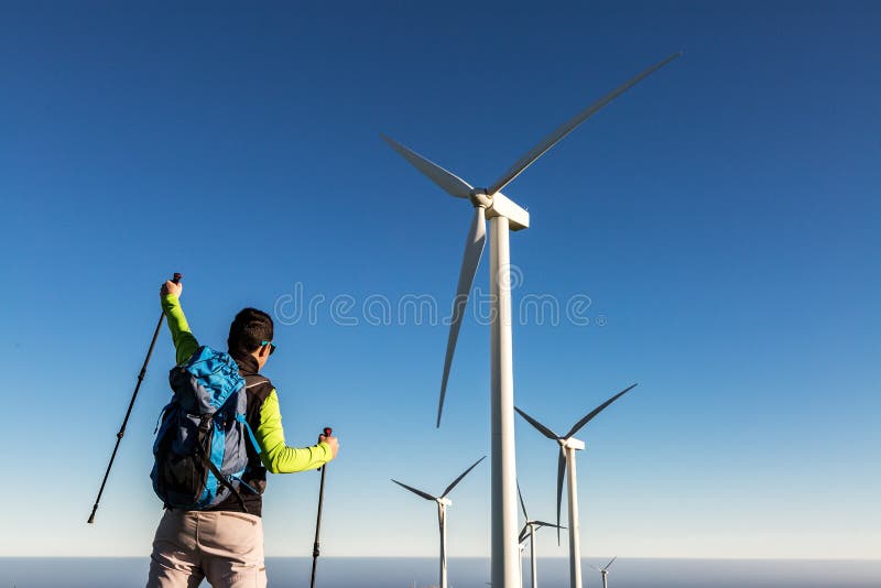Bărbat backpacker sărbătoare succes pe deal cu mori de vânt stock photography