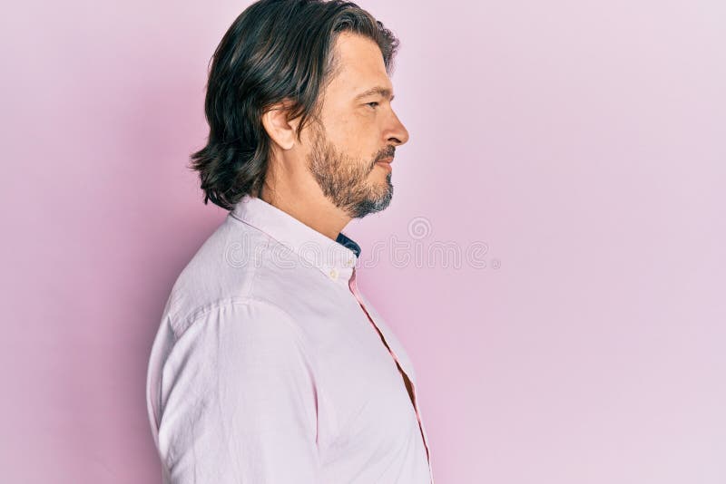 Bărbat chipeș de vârstă mijlocie, îmbrăcat în cămașă de afaceri în căutarea unui profil relaxat lateral, pozează cu fața naturală stock photography