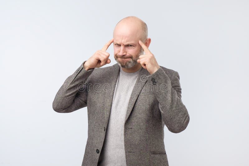 Bărbat european obosit și furios gestând cu degetul la templu încercând să-și amintească ceva stock photography