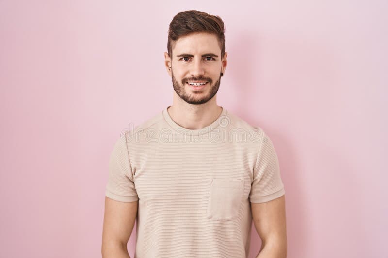 Bărbat hispanic cu barbă în picioare pe fond roz cu mâinile împreună și degetele încrucișate zâmbind relaxat și vesel stock images