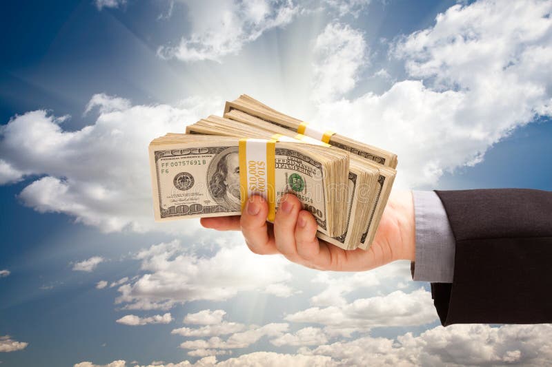 Bărbat ținând mână teanc de bani peste cer stock photo