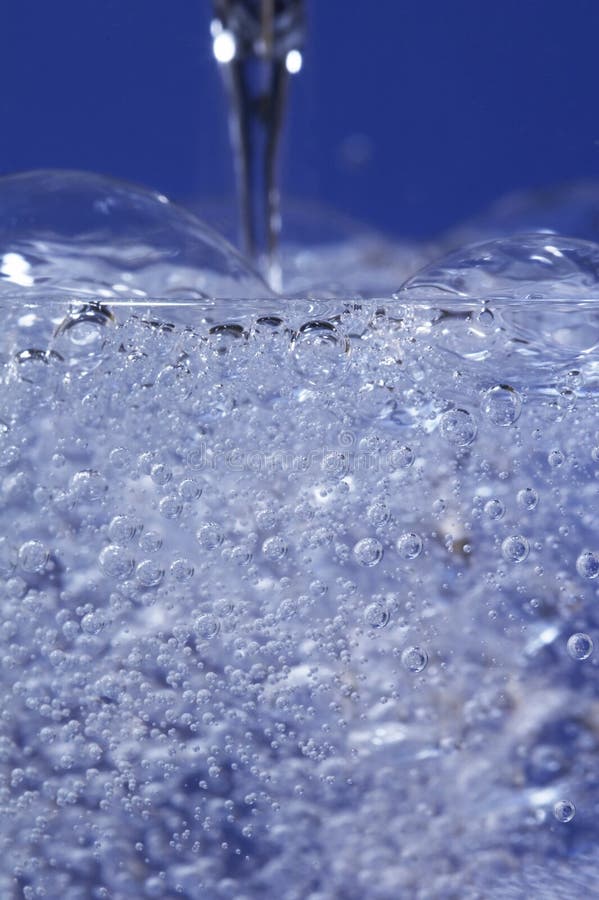 Sparkling water dropping in a glass with many bubbles. Sparkling water dropping in a glass with many bubbles