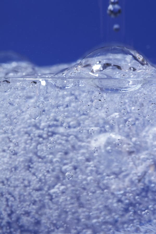 Sparkling water dropping in a glass with many bubbles. Sparkling water dropping in a glass with many bubbles