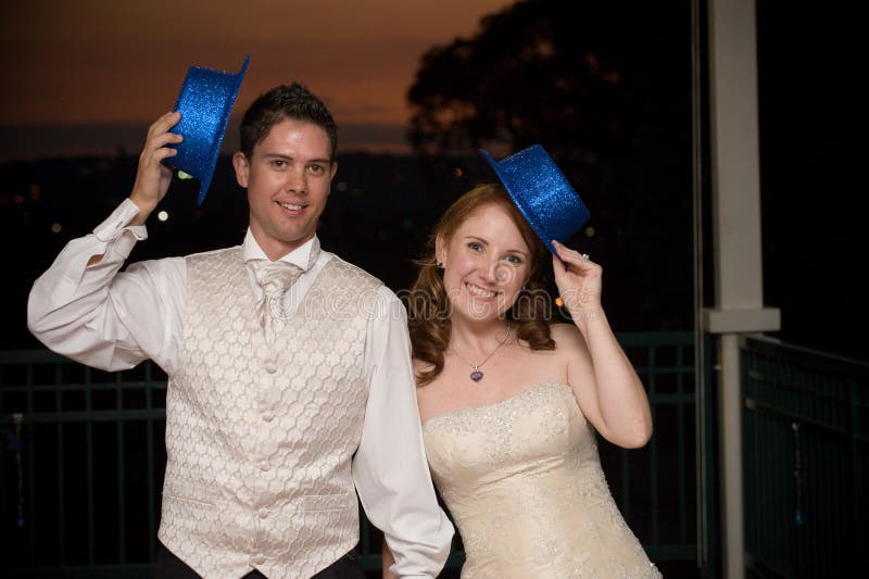 red head bride and her young handsome groom standing with blue hat at sunset outside whilst smiling. red head bride and her young handsome groom standing with blue hat at sunset outside whilst smiling