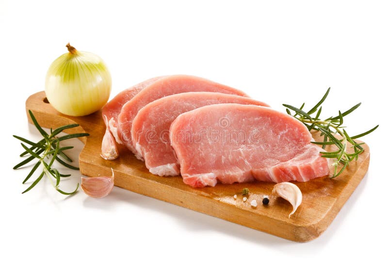Côtelettes de porc crues sur la planche à découper et les légumes images stock Côtelettes de porc crues sur la planche à découper et les légumes images stock