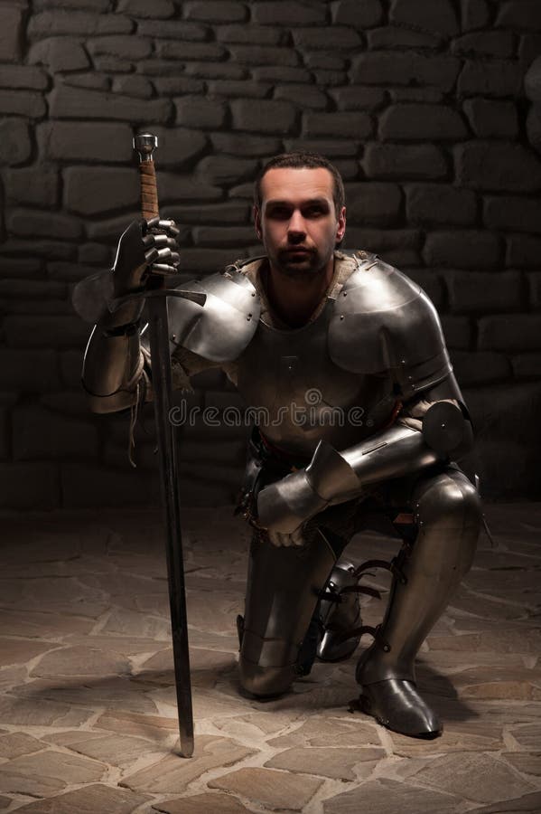 Caballero medieval que se arrodilla con la espada