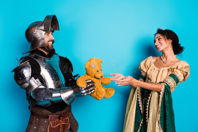 Caballeros y princesas con trajes de época compartiendo un oso de peluche que simboliza amistad y alegría fotos de archivo libres de regalías