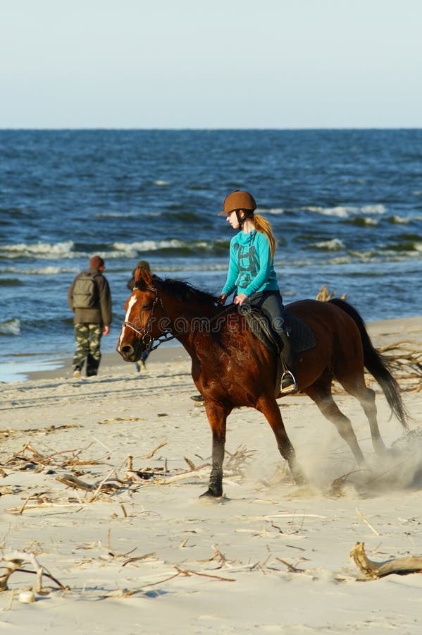 Caballo de montar a caballo de la mujer joven en la playa foto de archivo Caballo de montar a caballo de la mujer joven en la playa foto de archivo