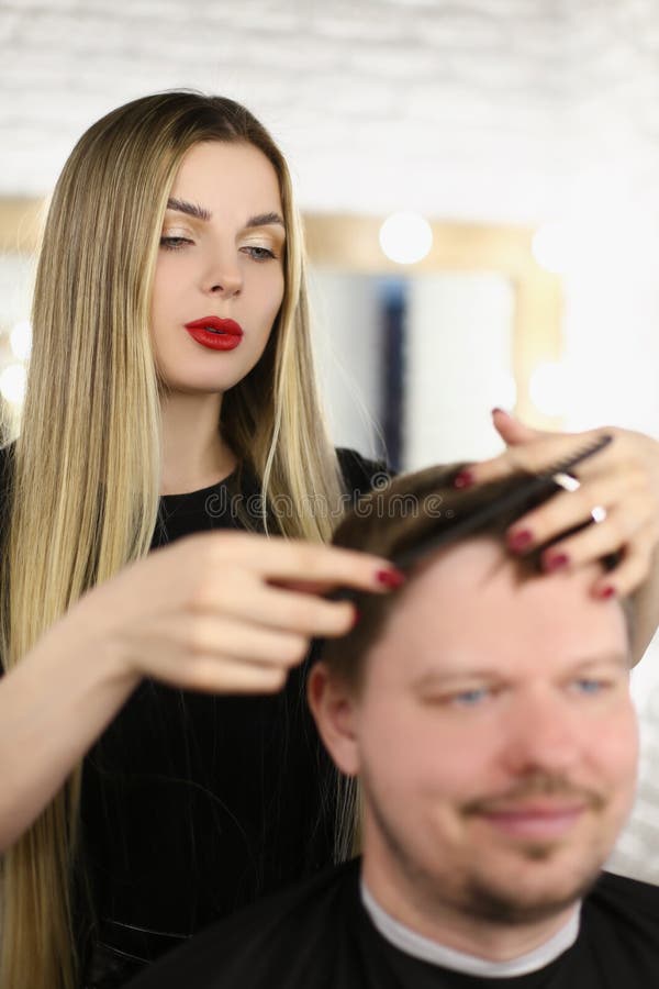 Cabeleireiro corta e penteia o cabelo com secador para senhora loira