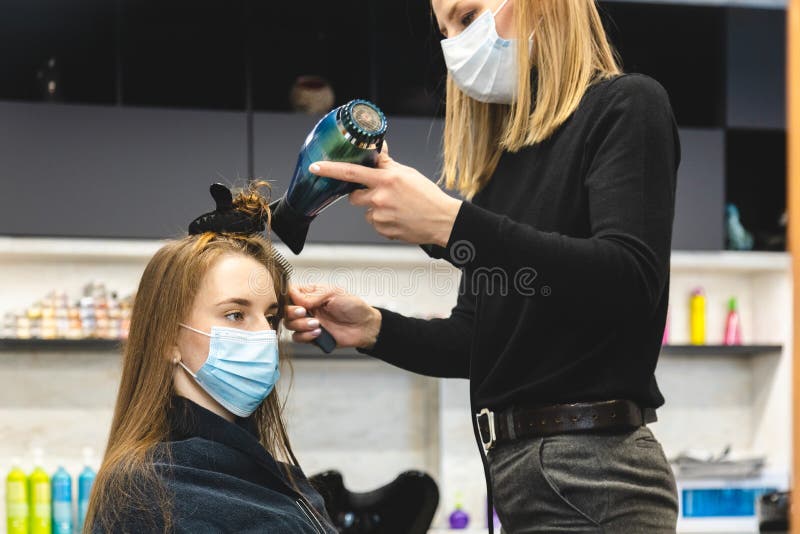 Cabeleireiro seca o cabelo com uma mulher de secador de cabelo no