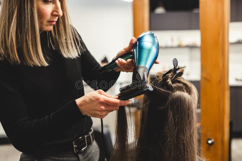 Cabeleireiro seca o cabelo com secador de cabelo para uma