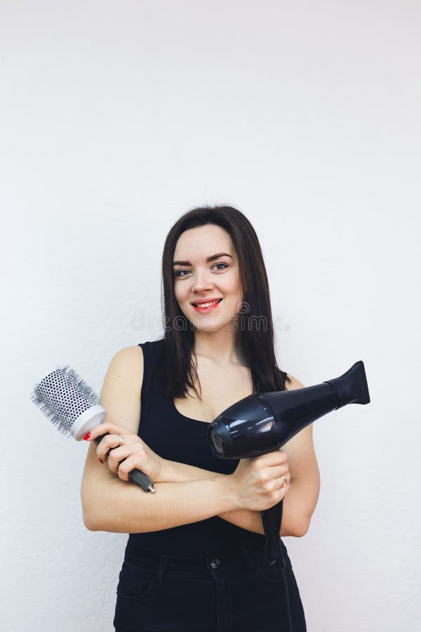 Cabeleireiro alegre, mulher posando com um secador de cabelo nas