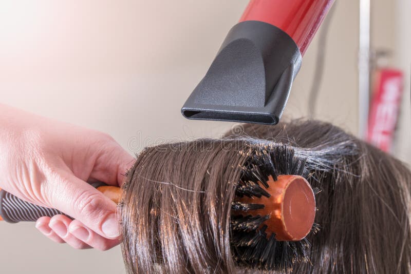 Cabeleireiro seca o cabelo com secador de cabelo para uma mulher após um  corte de cabelo no salão