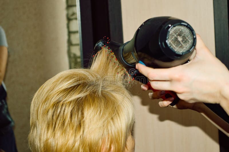 Cabeleireiro seca o cabelo com uma mulher de secador de cabelo no