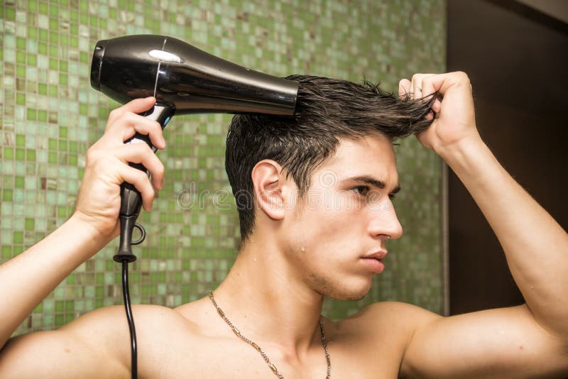 Cabello seco descamisado del hombre joven con el hairdryer fotografía de archivo Cabello seco descamisado del hombre joven con el hairdryer fotografía de archivo