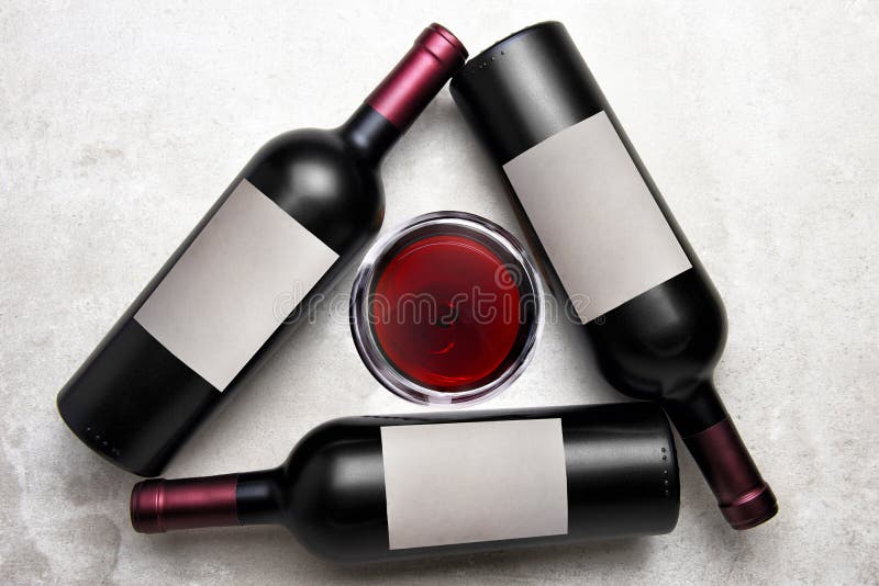 Cabernet Wine: Overhead view of a group of three bottles with blank labels arranged in a triangle with a glass of wine in the stock image