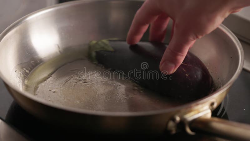Cabeça cozinhando fatia de beringela em frigideira de aço