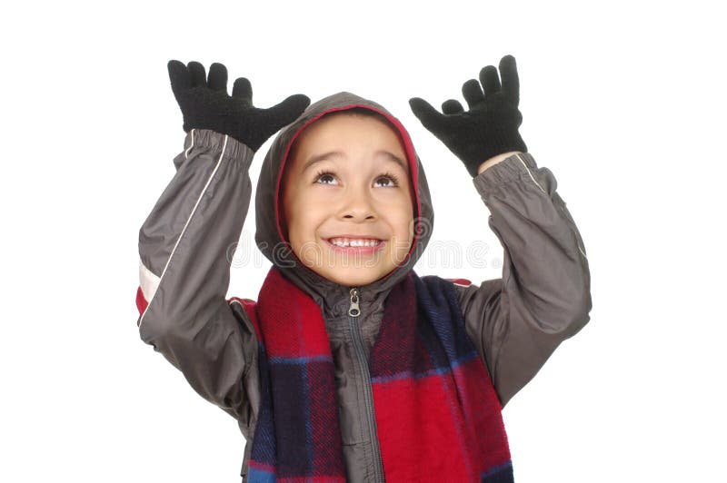 Boy in cold weather clothes looking up with hands raised, smiling, isolated on white background. Boy in cold weather clothes looking up with hands raised, smiling, isolated on white background