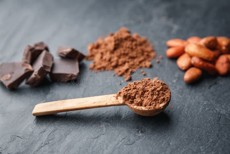Cacaopoeder in een houten lepel met cacaobonen en chocolade op een donkere achtergrond stock afbeeldingen Cacaopoeder in een houten lepel met cacaobonen en chocolade op een donkere achtergrond stock afbeeldingen