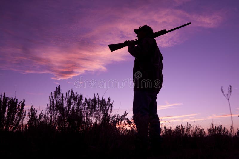 Cacciatore con il fucile da caccia nel tramonto immagine stock libera da diritti Cacciatore con il fucile da caccia nel tramonto immagine stock libera da diritti