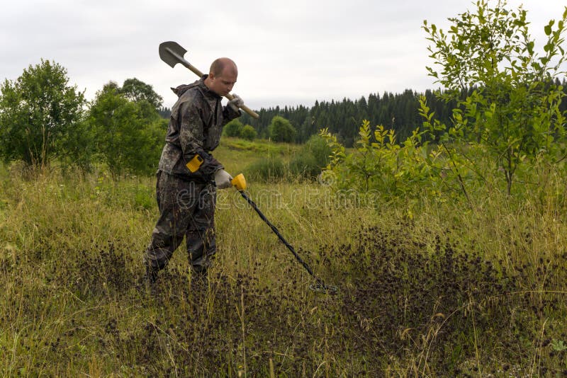 Treasure hunter with a shovel and metal detector in a natural landscape. Treasure hunter with a shovel and metal detector in a natural landscape