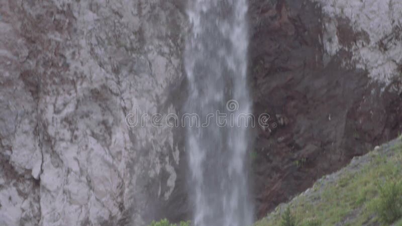 A cachoeira flui para baixo sobre o penhasco rochoso nas montanhas