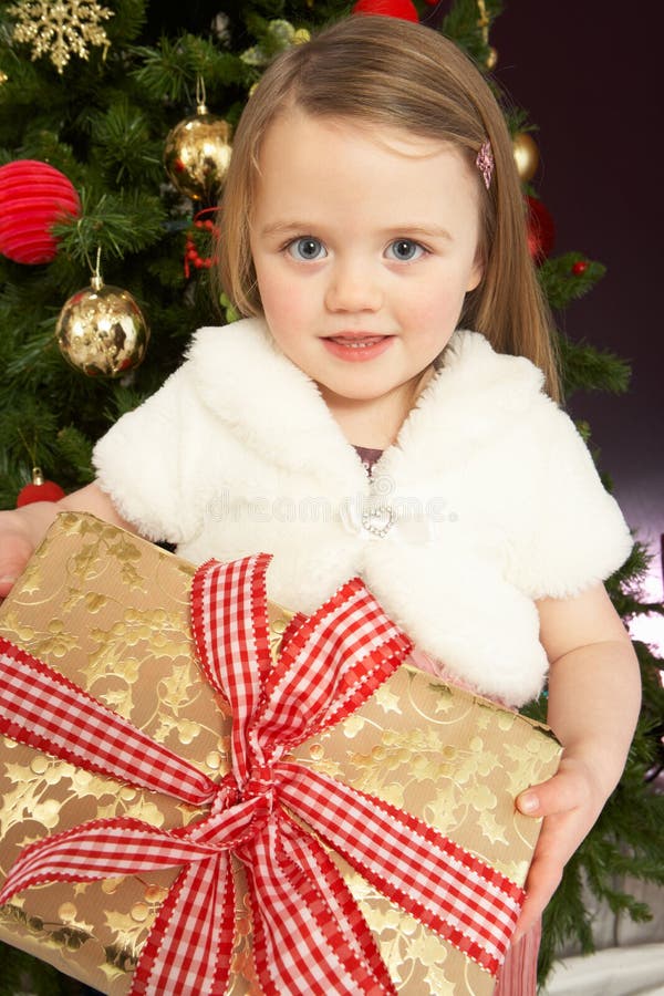 Cadeau de fixation de jeune fille devant l'arbre de Noël photo libre de droits Cadeau de fixation de jeune fille devant l'arbre de Noël photo libre de droits