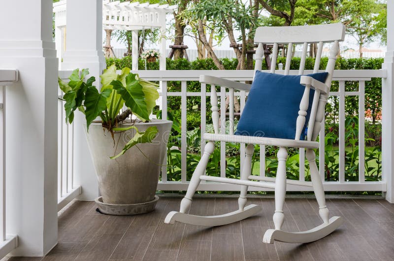 Cadeira de balanço de madeira branca no pátio de entrada coberto em casa