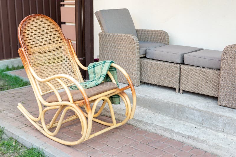 Cadeira de balanço de madeira vazia do rattan com a manta verde da flanela no quintal do terraço da casa fora Exterior calmo da c imagem de stock royalty free Cadeira de balanço de madeira vazia do rattan com a manta verde da flanela no quintal do terraço da casa fora Exterior calmo da c imagem de stock royalty free