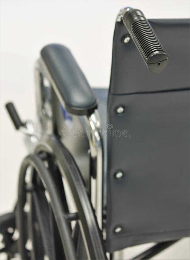 An empty black wheelchair, like those used in hospitals and medical facilities, with a focus on the back handle. An empty black wheelchair, like those used in hospitals and medical facilities, with a focus on the back handle.