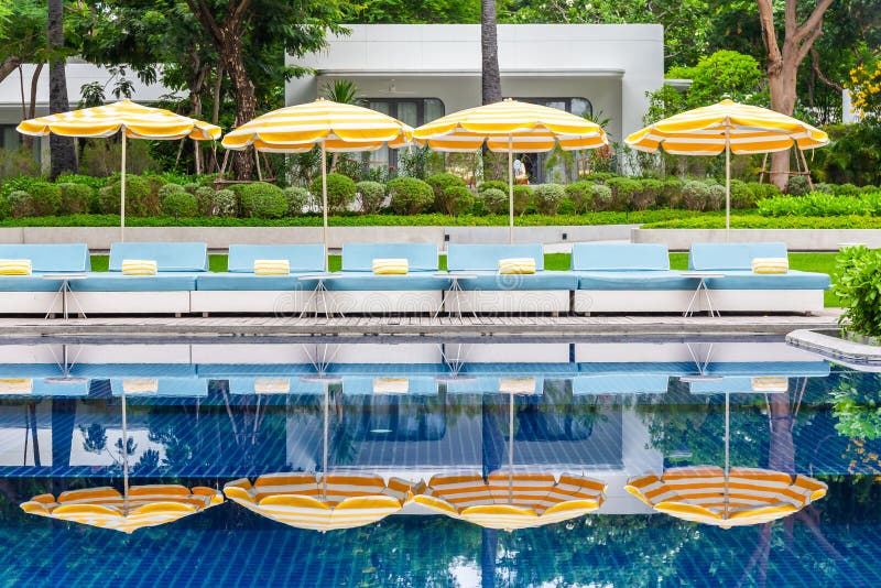 Pool chairs with umbrellas and beautiful water reflections by the sea with toddy palms in the background. Pool chairs with umbrellas and beautiful water reflections by the sea with toddy palms in the background