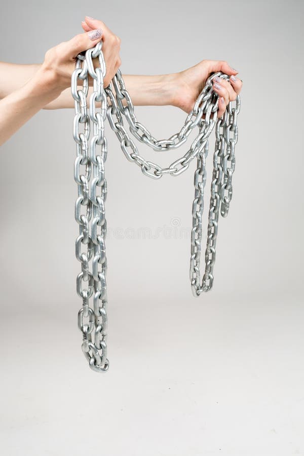 Cadena gruesa del metal en las manos de las mujeres en el fondo blanco aislado fotografía de archivo libre de regalías Cadena gruesa del metal en las manos de las mujeres en el fondo blanco aislado fotografía de archivo libre de regalías