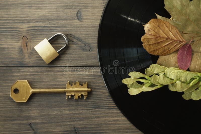 Cadenas en laiton et clé à côté de disque vinyle de vintage image stock Cadenas en laiton et clé à côté de disque vinyle de vintage image stock