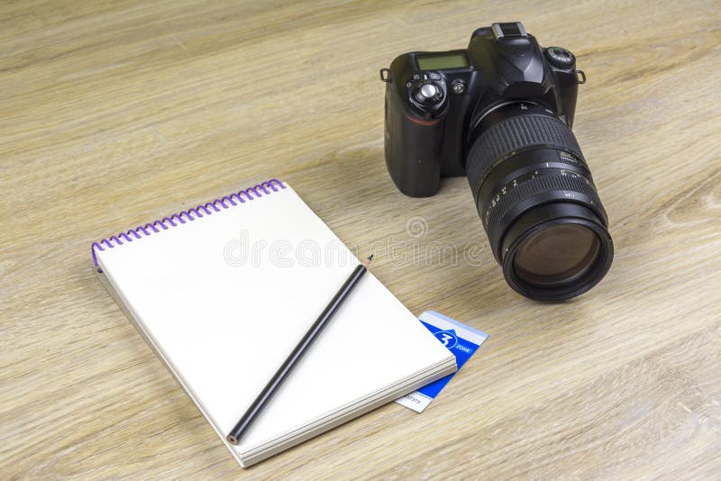 Caderno com a câmera dos lápis e da foto de SLR na textura de madeira imagens de stock Caderno com a câmera dos lápis e da foto de SLR na textura de madeira imagens de stock